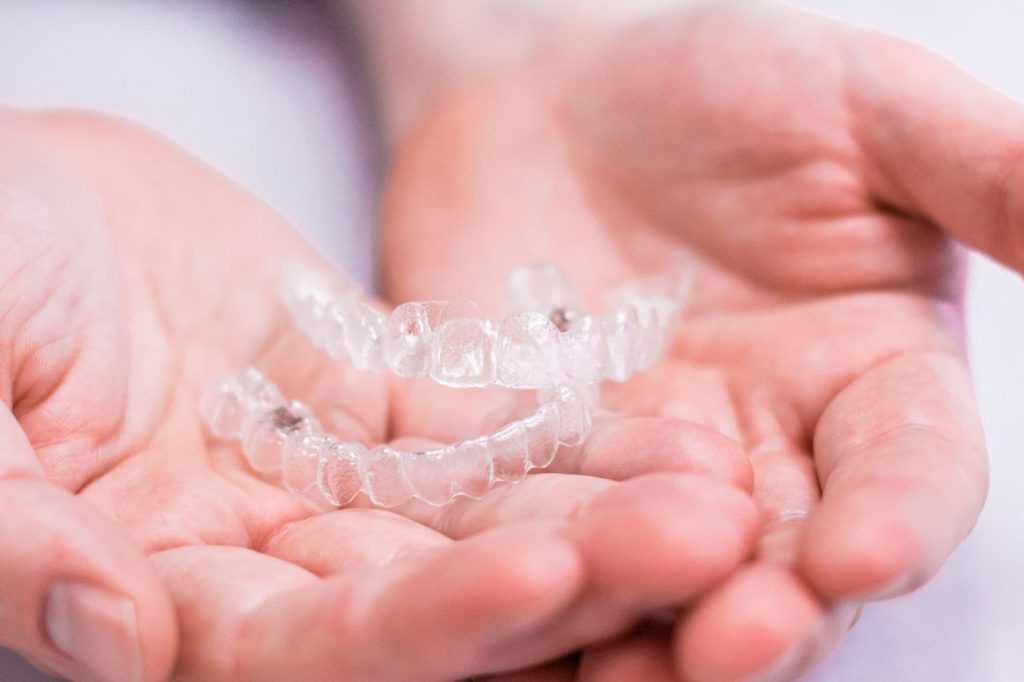Clear aligners held in hands, showcasing Invisalign treatment options at Foley Orthodontics in Cary, NC, emphasizing comfort and convenience of orthodontic care.