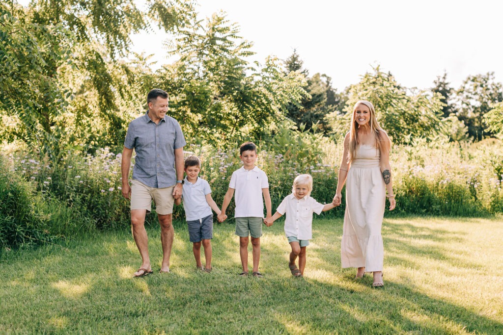 Family walking together in a green park, showcasing smiles and togetherness, reflecting the importance of orthodontic care like Invisalign and clear aligners for all ages at Foley Orthodontics in Cary, NC.